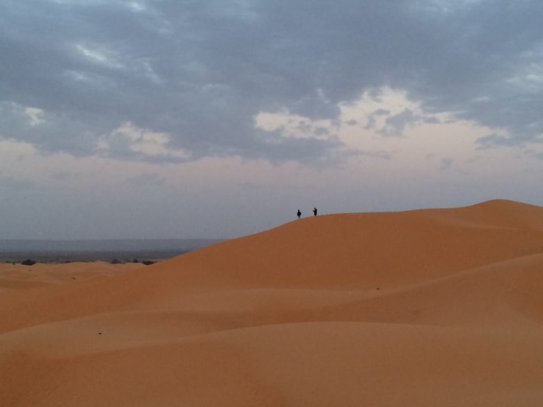 Tiny figures atop a neighboring dune